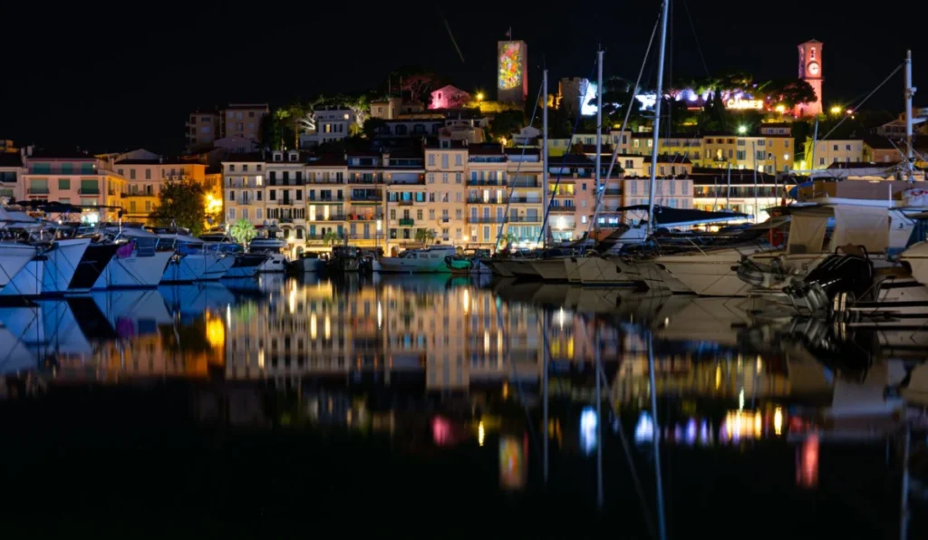 Cannes Old Port and Le Suquet lit up at night, with yachts reflected in the water