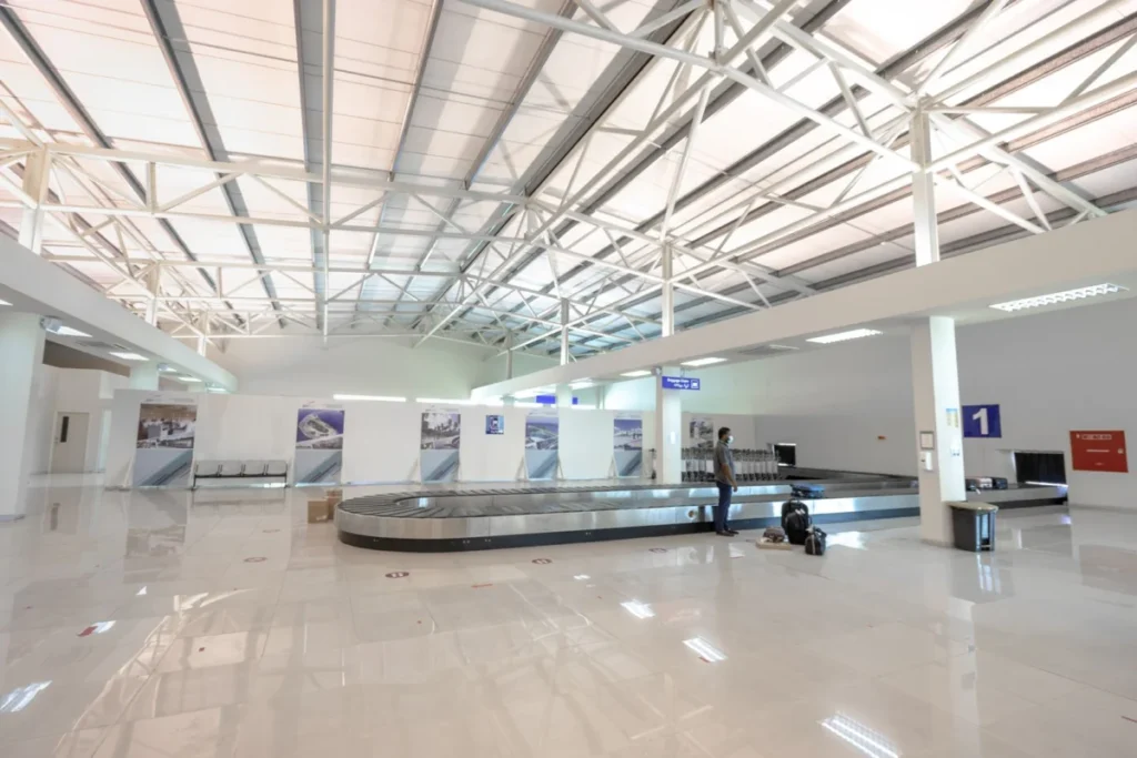 Traveller waiting at an airport baggage claim belt before walking to the ride app pickup