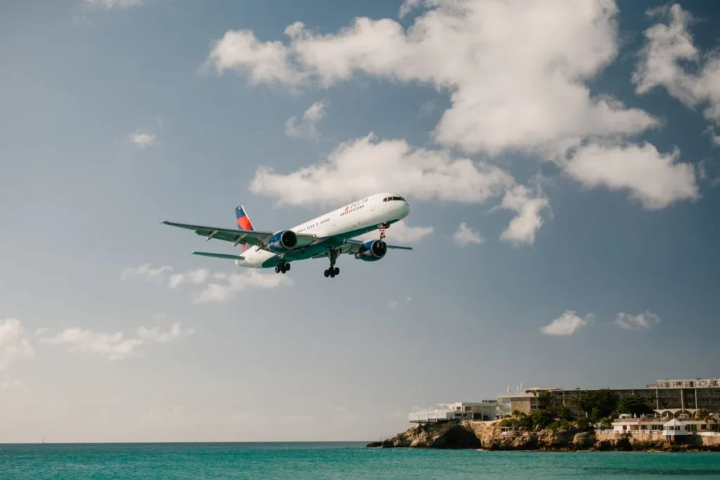 Passenger jet on final approach over turquoise sea, like arrivals into Nice Côte d'Azur Airport