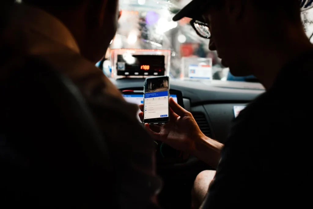 Passengers checking a ride app on a phone in a car at night