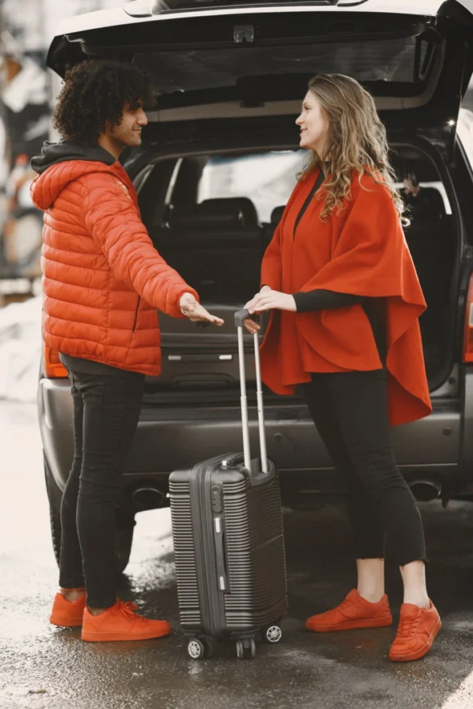 Two travellers loading a suitcase into a car boot, the luggage question every airport pickup raises